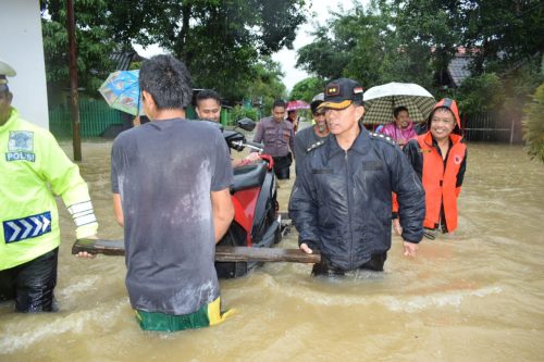 Kapolres Barru AKBP Burhaman membantu evakuasi satu unit sepeda motor di tengah luapan banjir.
